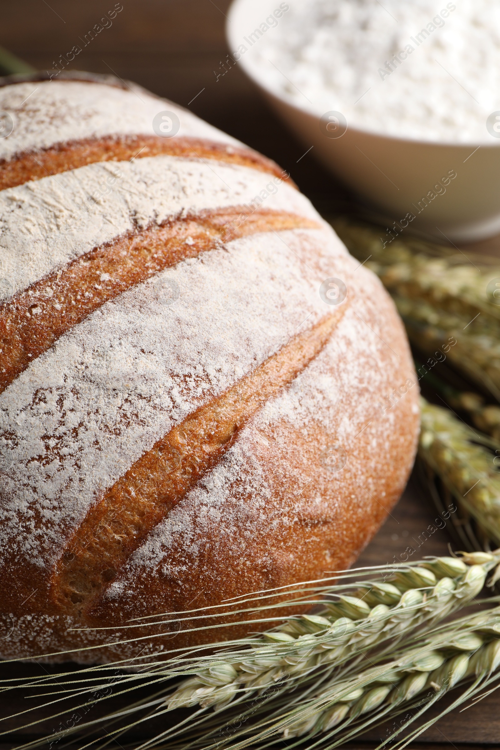 Photo of Fresh bread, flour and green wheat spikes on table, closeup