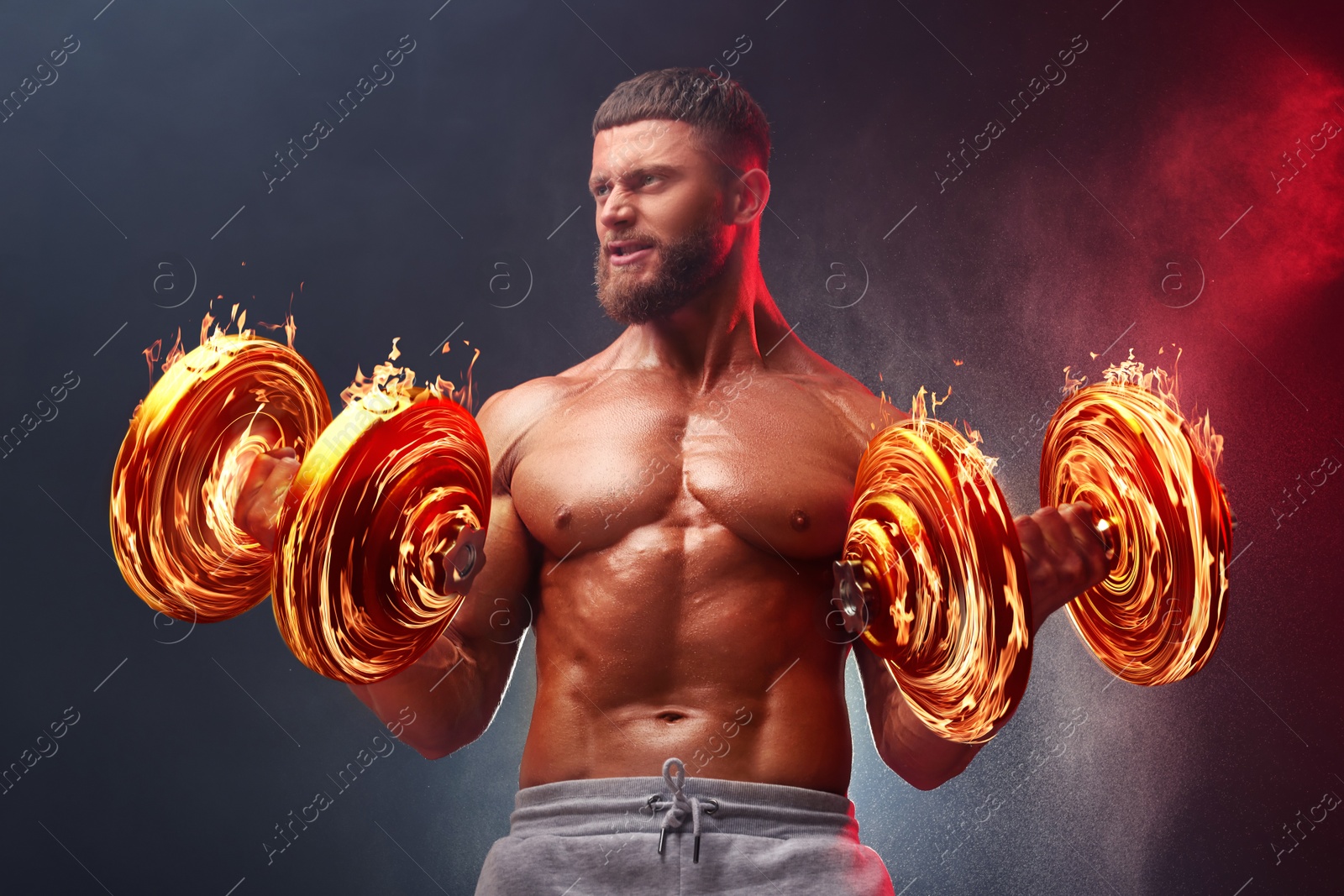 Image of Bodybuilder exercising with flaming dumbbells in smoke against dark background