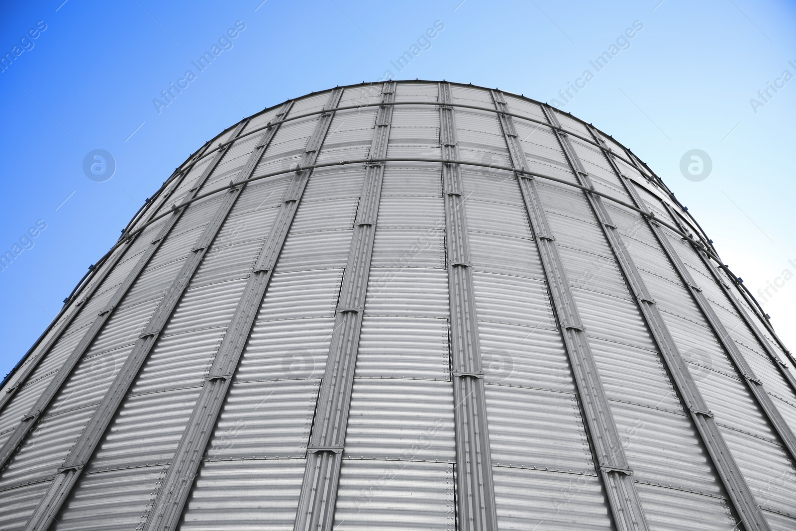 Image of Modern granary for storing cereal grains against blue sky, low angle view