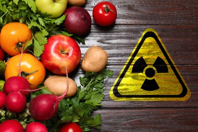 Image of Fresh vegetables on wooden table and radioactive sign, top view. Environmental contamination, polluted food
