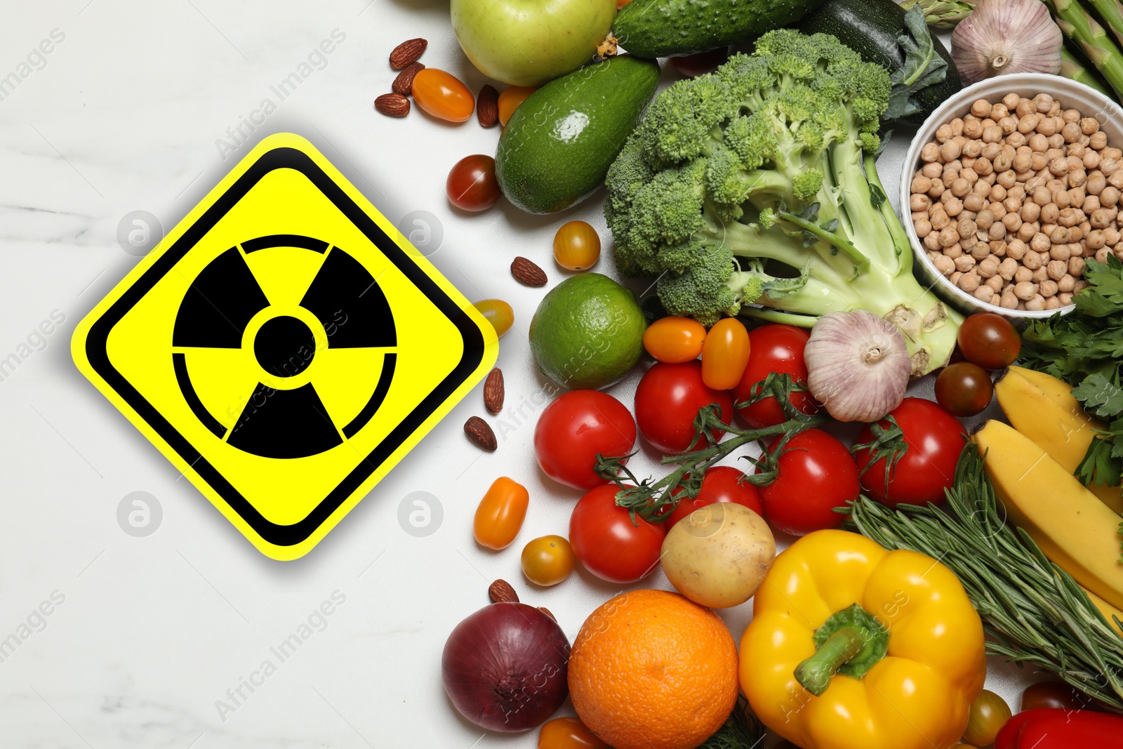 Image of Fresh vegetables, fruits and chickpea on white marble table and radioactive sign, top view. Environmental contamination, polluted food