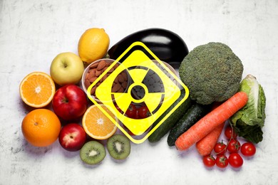 Image of Fresh vegetables and fruits on white table and radioactive sign, top view. Environmental contamination, polluted food