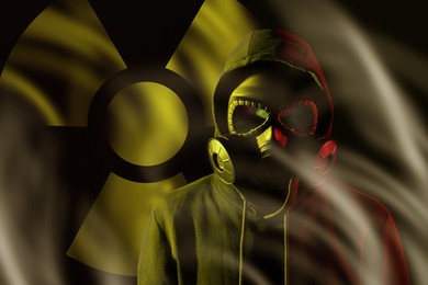 Image of Man wearing gas mask in smoke against black background. Radioactive sign behind him