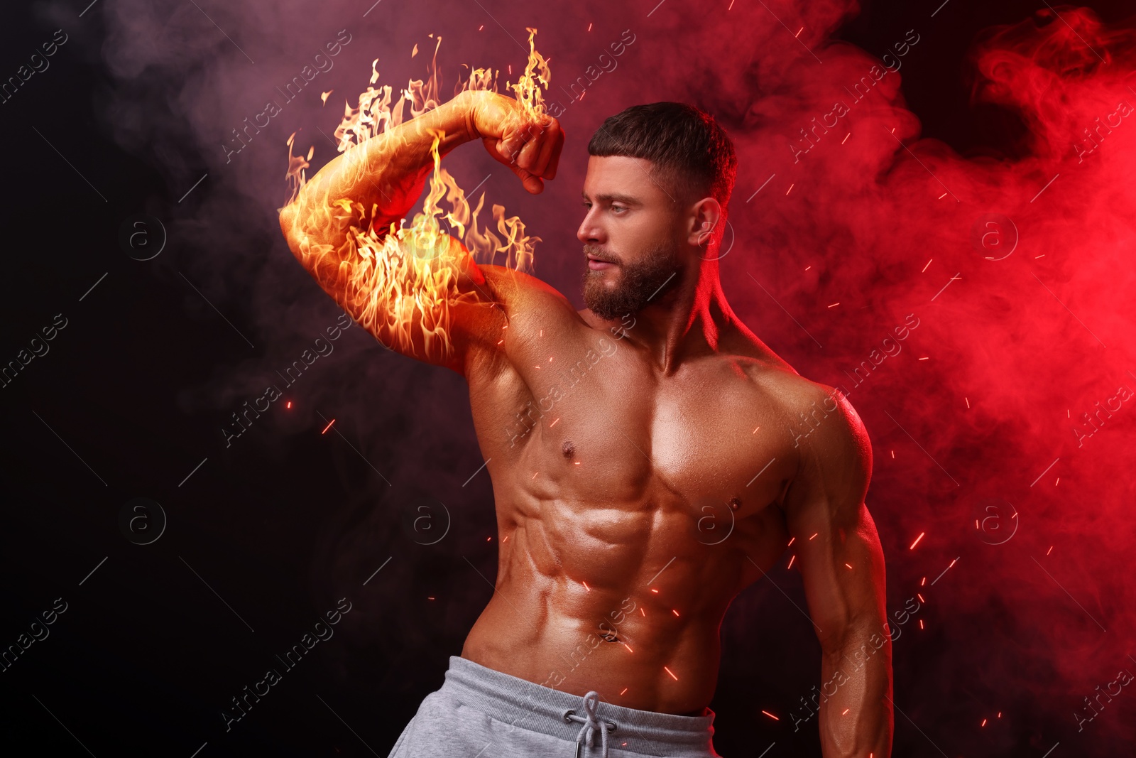 Bodybuilder showing his biceps in smoke against dark background. Muscular man with flaming arm Image of Bodybuilder showing his biceps in smoke against dark background. Muscular man with flaming arm
