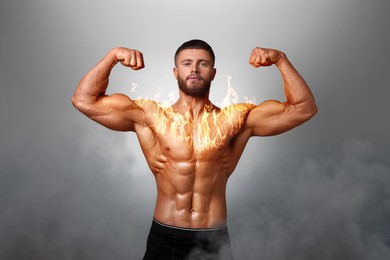 Image of Bodybuilder showing his biceps against grey background. Muscular man with flaming chest