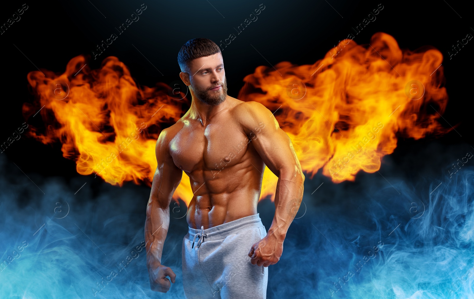 Image of Bodybuilder with flaming wings behind his back against dark background. Shirtless muscular man in smoke