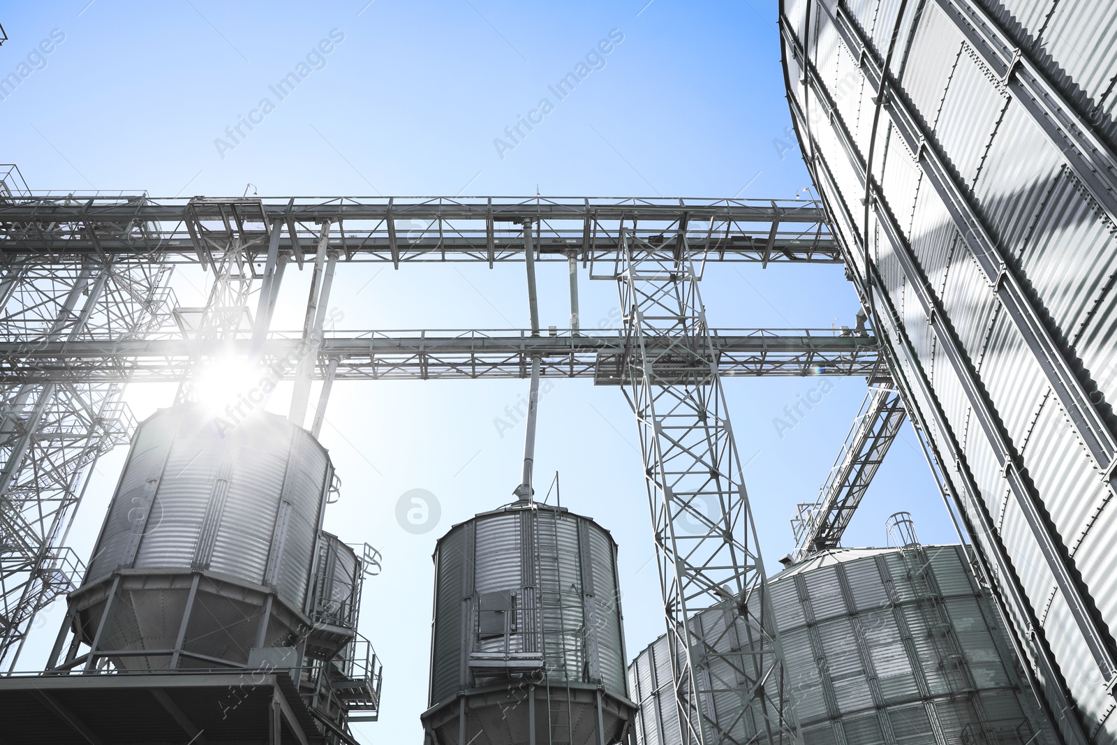 Image of Modern granaries for storing cereal grains against blue sky, low angle view