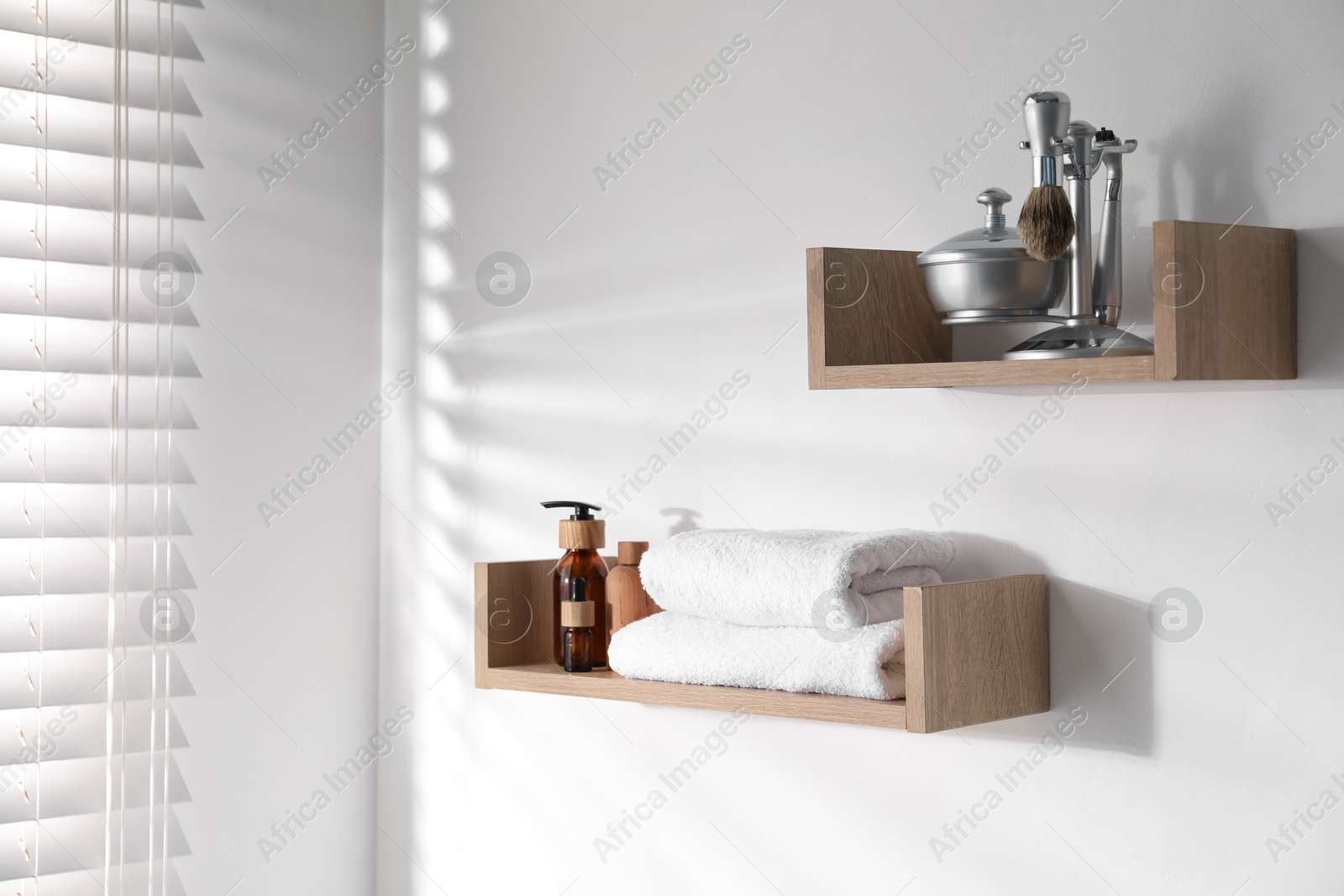 Wooden shelves with bathroom necessities on white wall Photo of Wooden shelves with bathroom necessities on white wall