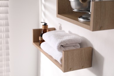 Photo of Wooden shelves with bathroom necessities on white wall