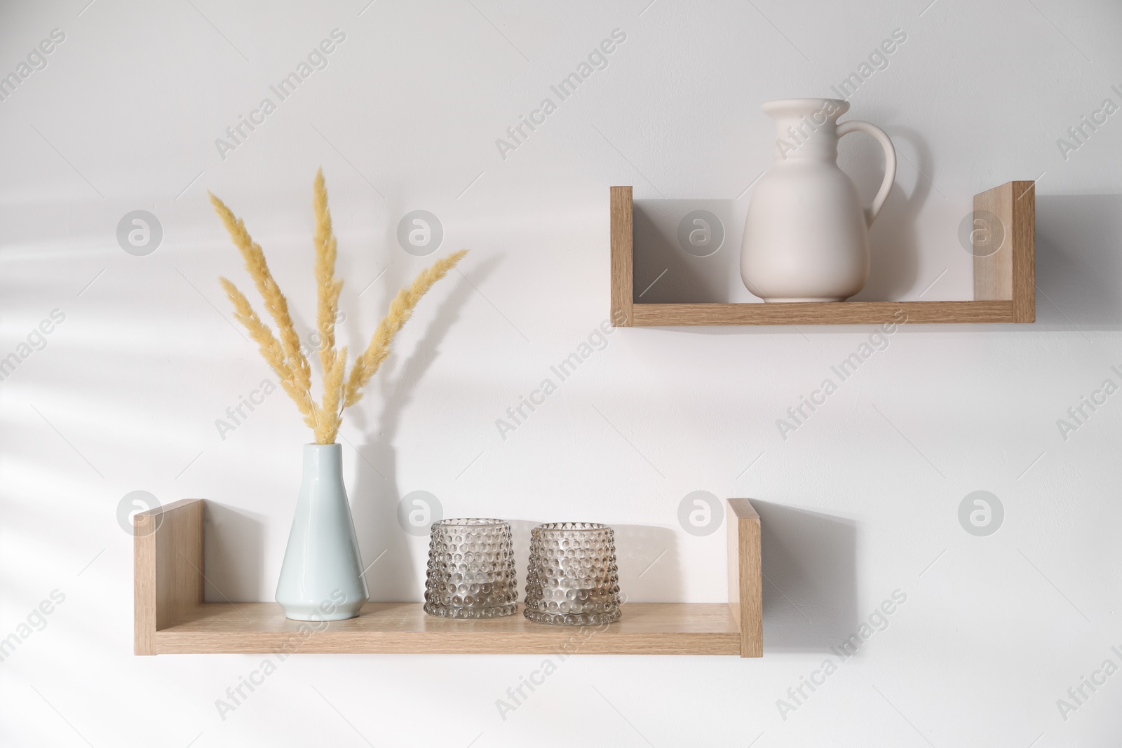 Wooden shelves with tableware and spikes in vase on white background Photo of Wooden shelves with tableware and spikes in vase on white background