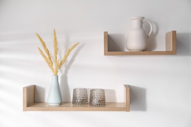 Photo of Wooden shelves with tableware and spikes in vase on white background