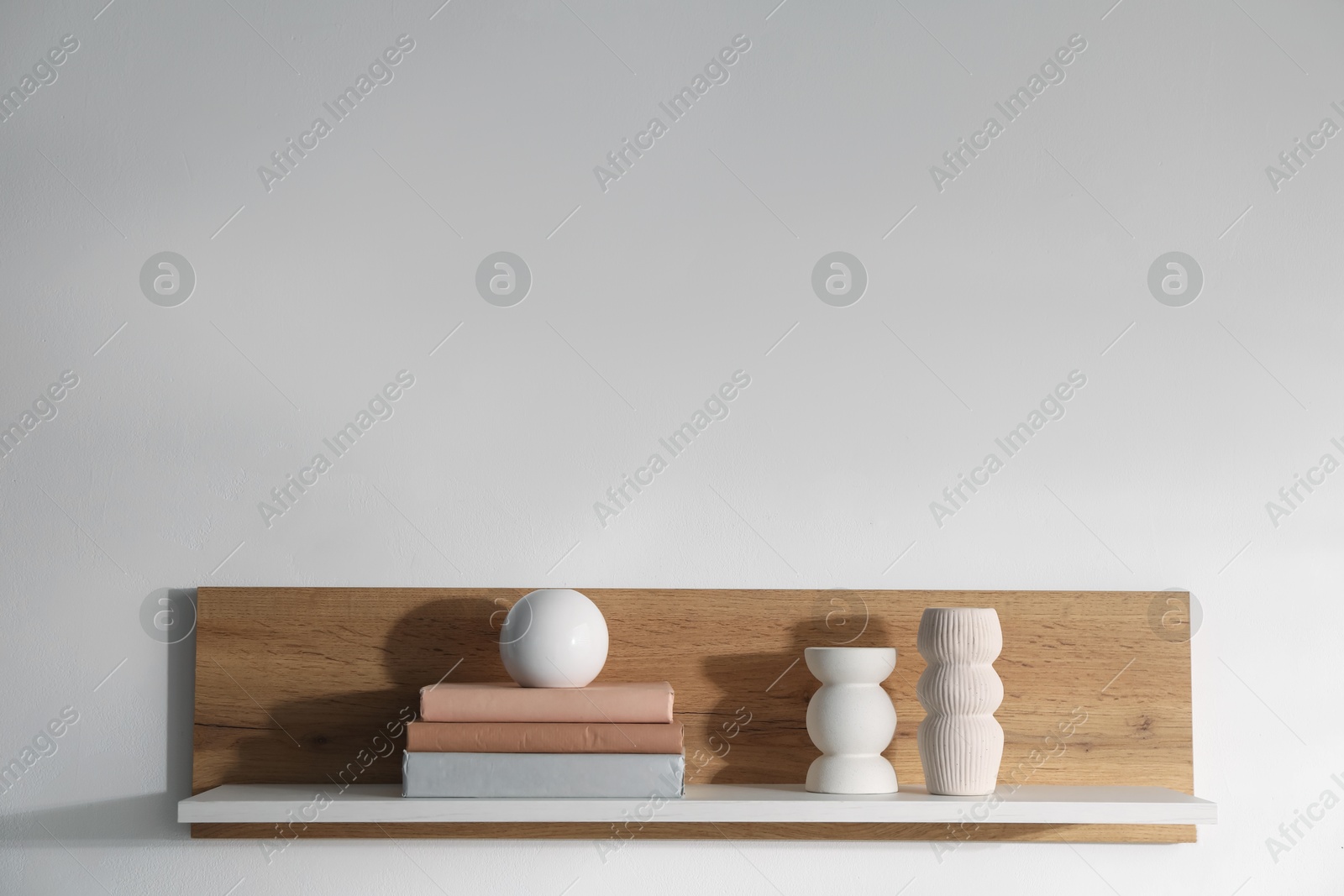 Wooden shelf with books and decor on white background. Space for text Photo of Wooden shelf with books and decor on white background. Space for text