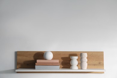 Photo of Wooden shelf with books and decor on white background. Space for text