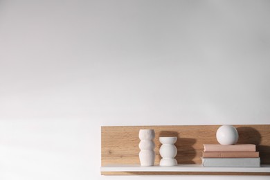 Photo of Wooden shelf with books and decor on white background. Space for text