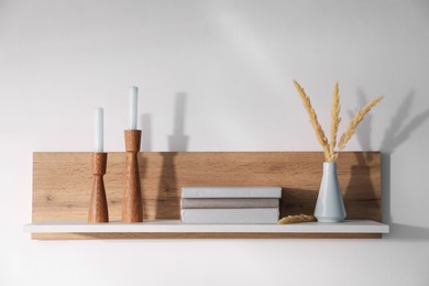 Photo of Wooden shelf with books and decor on white background