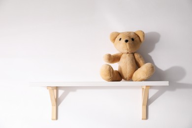 Photo of Shelf with teddy bear on white background. Space for text