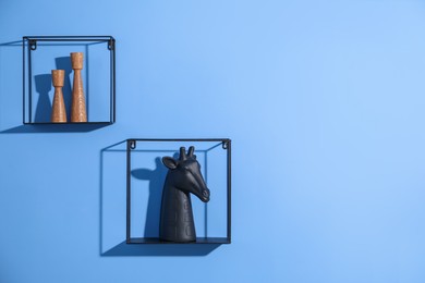 Photo of Metal shelves with stylish decor on blue background. Space for text