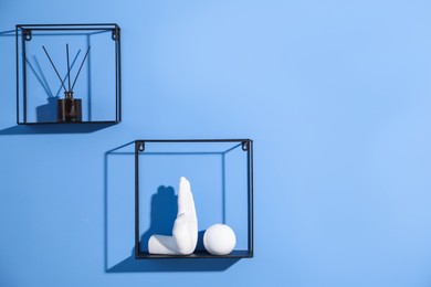 Photo of Metal shelves with stylish decor on blue background. Space for text