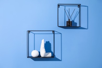 Photo of Metal shelves with stylish decor on blue background