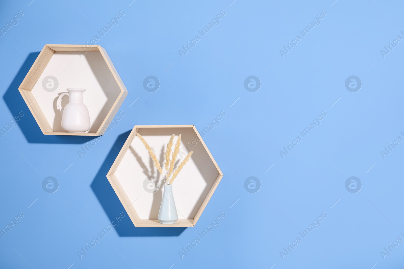 Honeycomb shaped shelves with decor on blue background. Space for text Photo of Honeycomb shaped shelves with decor on blue background. Space for text