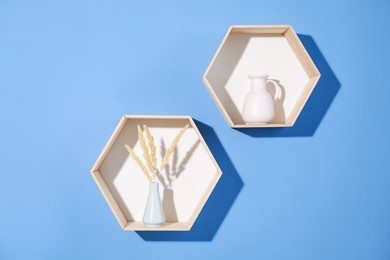 Photo of Honeycomb shaped shelves with decor on blue background