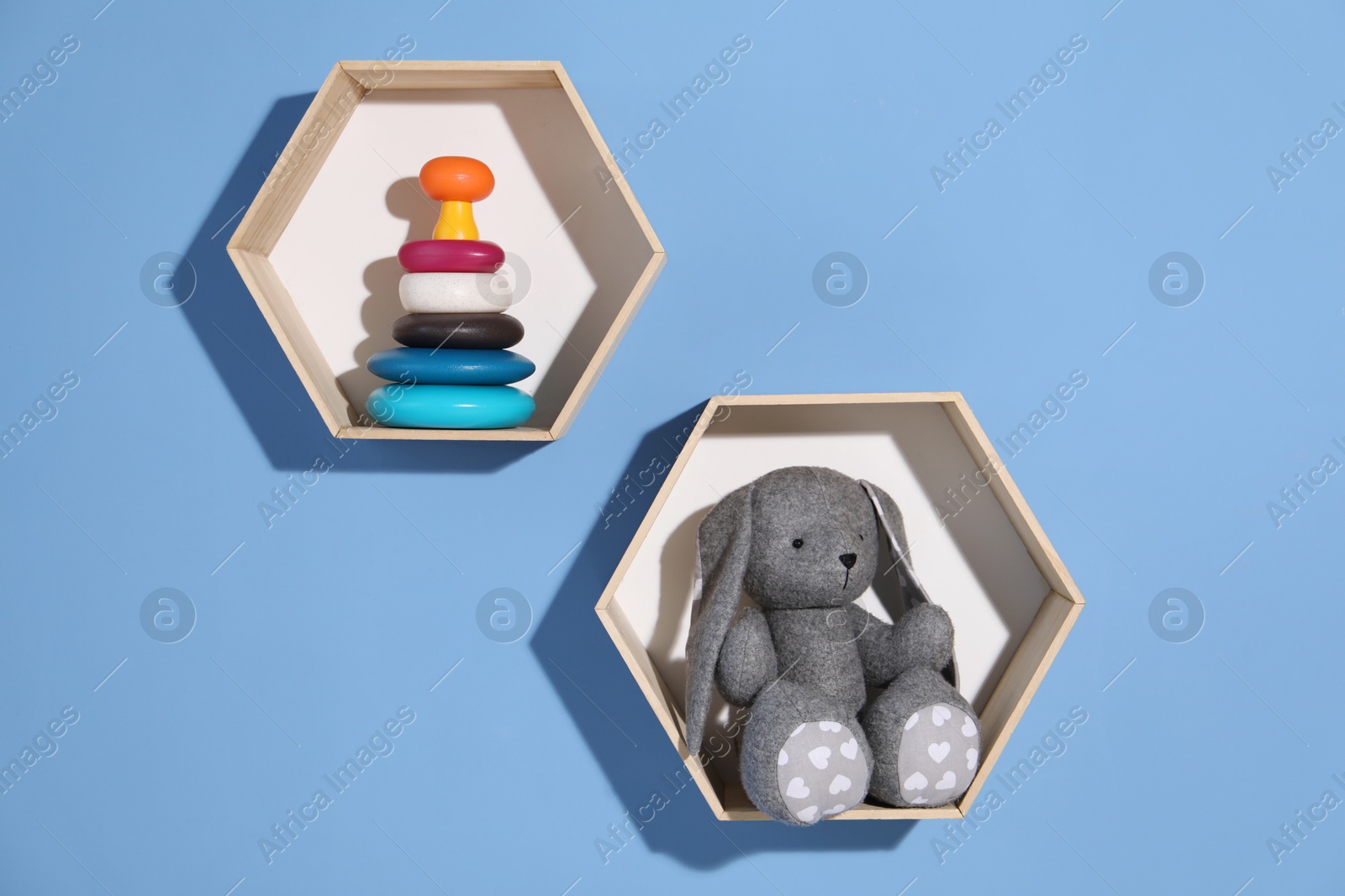 Honeycomb shaped shelves with different toys on blue background Photo of Honeycomb shaped shelves with different toys on blue background
