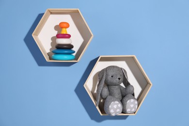 Photo of Honeycomb shaped shelves with different toys on blue background