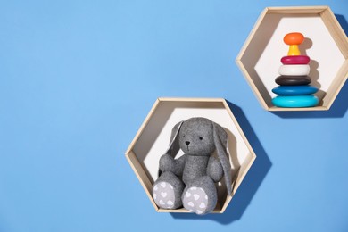 Photo of Honeycomb shaped shelves with different toys on blue background. Space for text