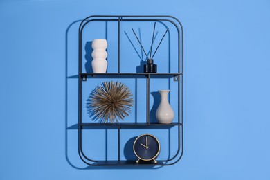 Photo of Metal shelves with stylish decor on blue background