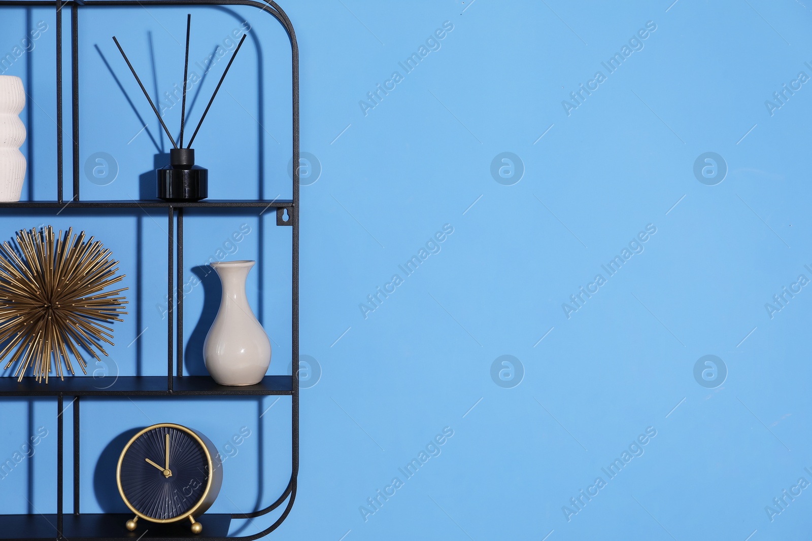 Metal shelves with stylish decor on blue background. Space for text Photo of Metal shelves with stylish decor on blue background. Space for text