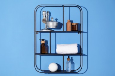 Photo of Metal shelving unit with towel and cosmetic products on blue background