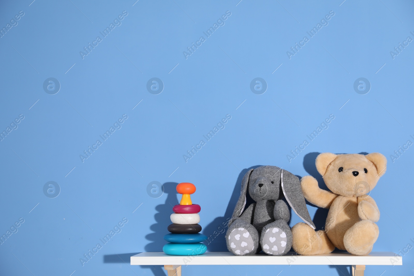 Shelf with different toys on blue background. Space for text Photo of Shelf with different toys on blue background. Space for text