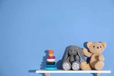 Photo of Shelf with different toys on blue background. Space for text