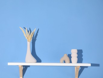 Photo of Shelf with beautiful decor on blue background. Space for text