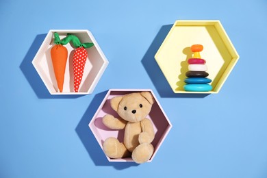 Photo of Honeycomb shaped shelves with different toys on blue background