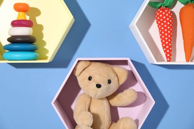 Photo of Honeycomb shaped shelves with different toys on blue background