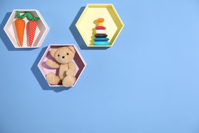 Photo of Honeycomb shaped shelves with different toys on blue background. Space for text
