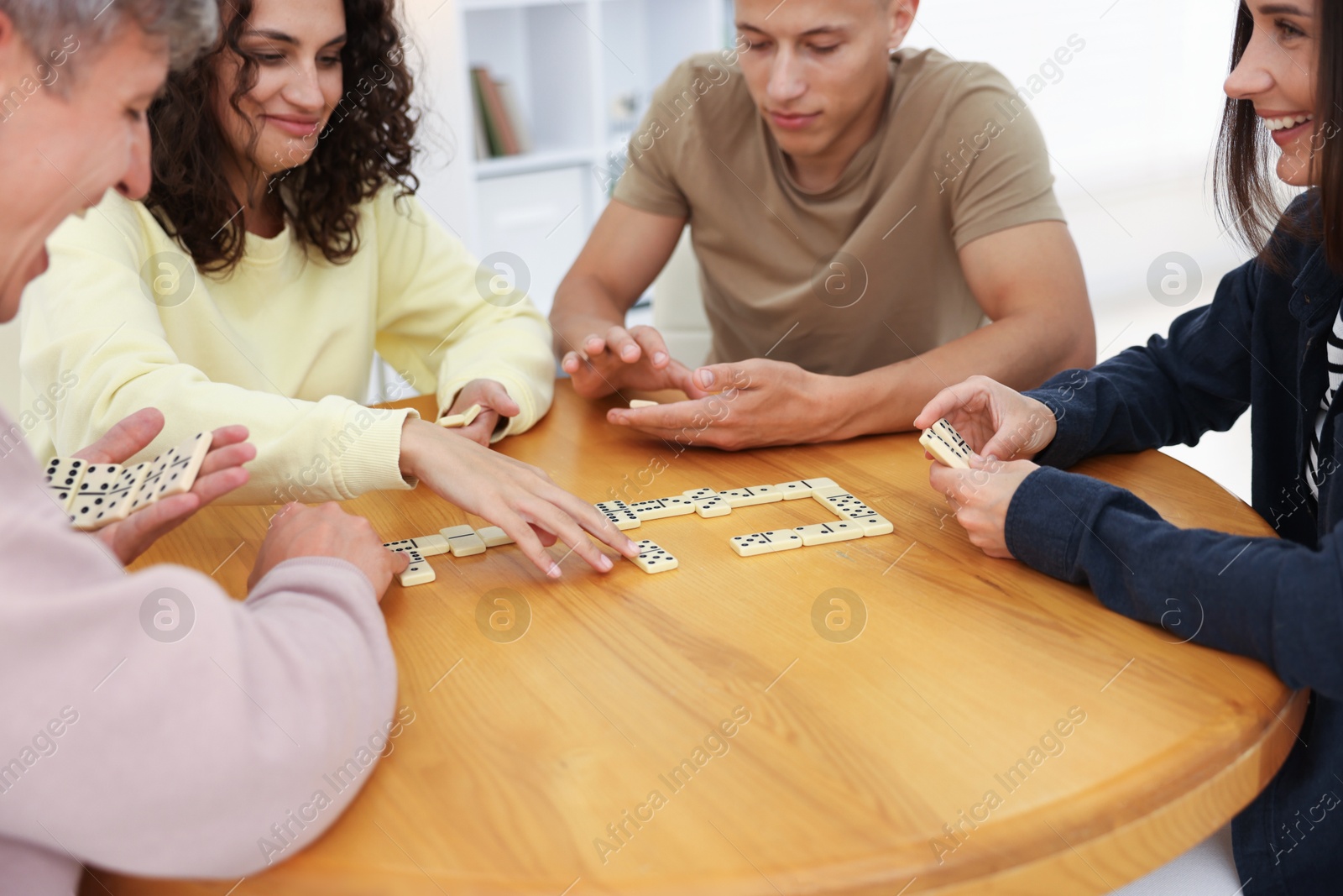 Friends playing dominoes at wooden table indoors Photo of Friends playing dominoes at wooden table indoors