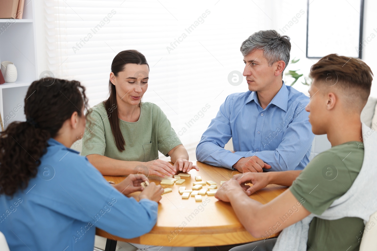 Friends playing dominoes at wooden table indoors Photo of Friends playing dominoes at wooden table indoors