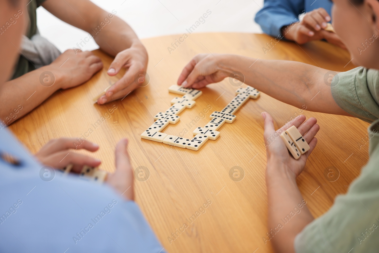 Friends playing dominoes at wooden table, closeup Photo of Friends playing dominoes at wooden table, closeup