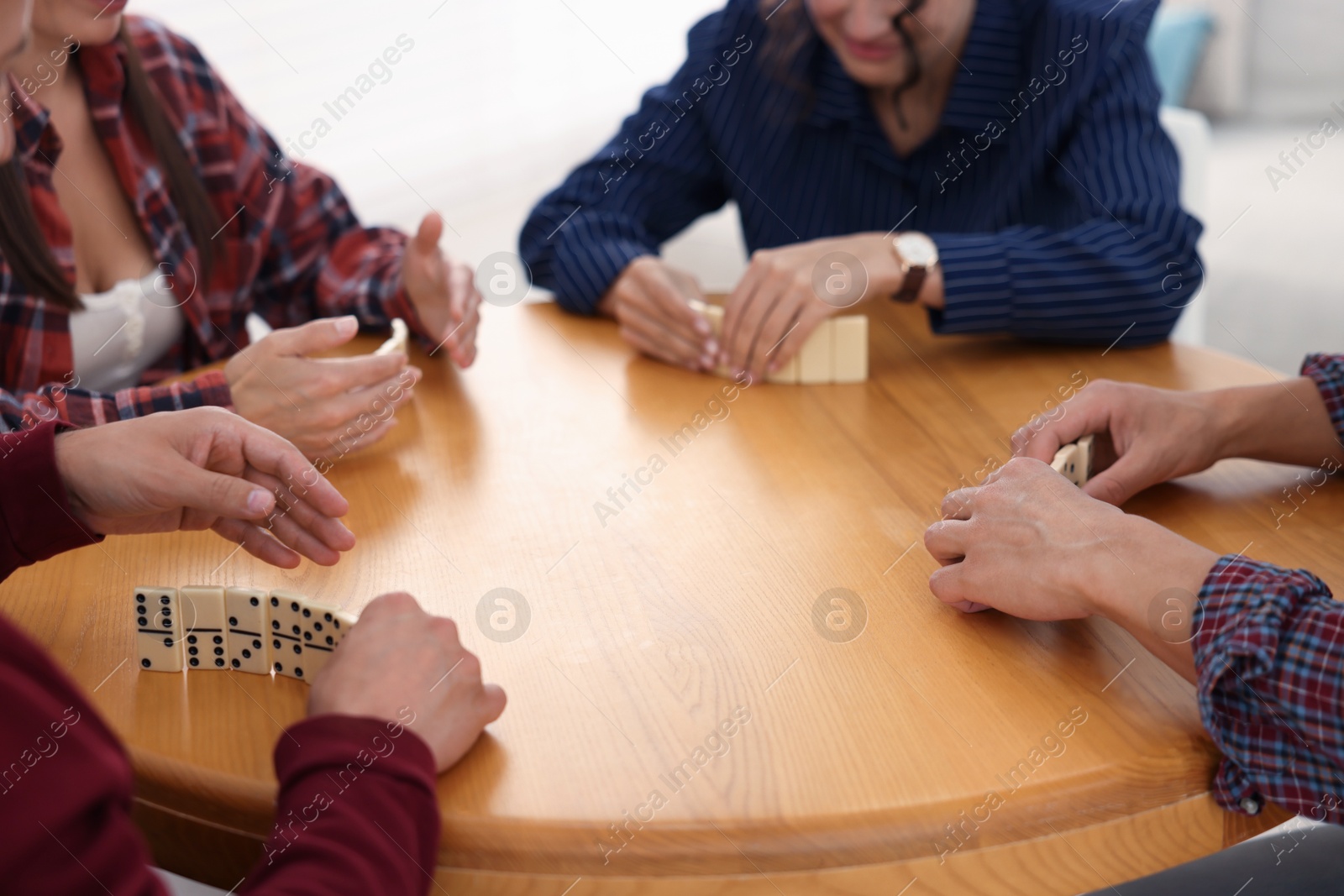 Friends playing dominoes at wooden table indoors, closeup Photo of Friends playing dominoes at wooden table indoors, closeup