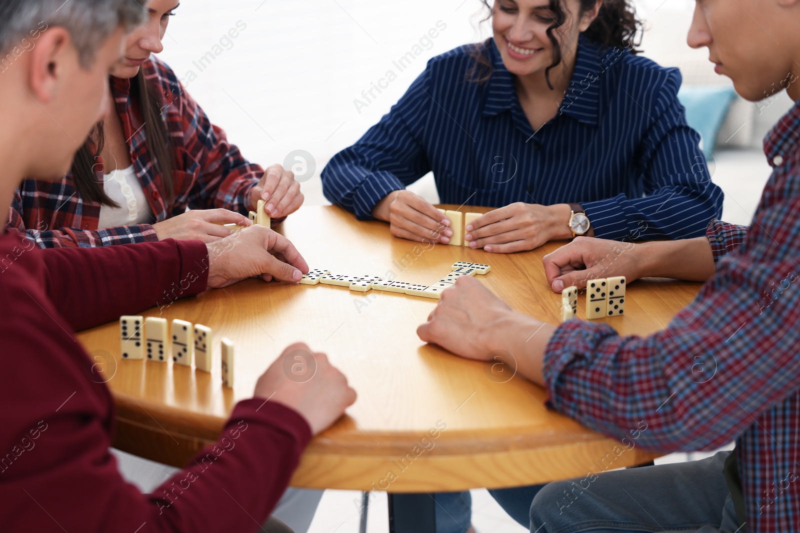 Friends playing dominoes at wooden table indoors, closeup Photo of Friends playing dominoes at wooden table indoors, closeup