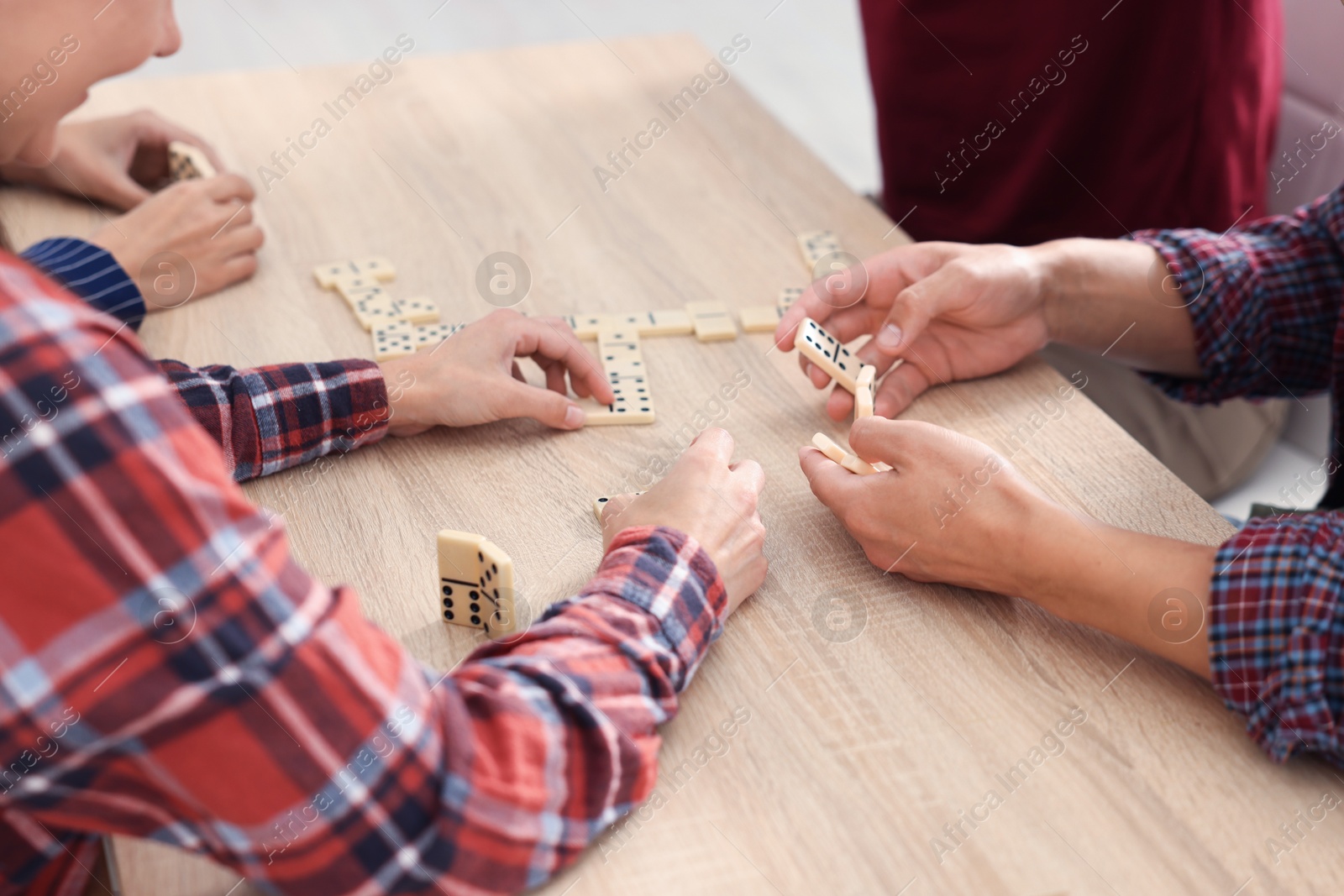 Friends playing dominoes at light wooden table, closeup Photo of Friends playing dominoes at light wooden table, closeup