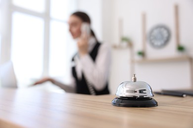 Photo of Receptionist talking with client by phone in hotel, focus on service bell
