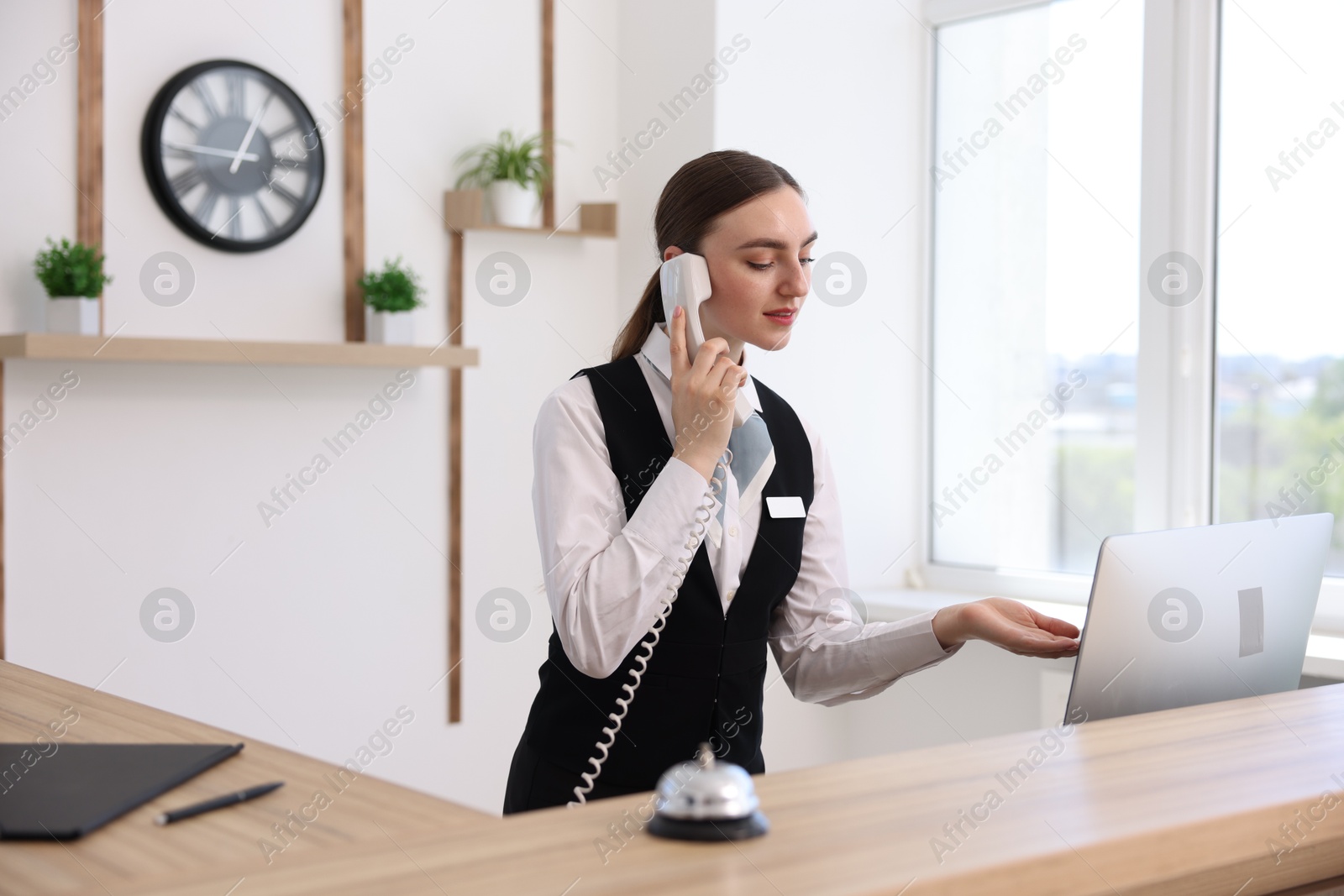 Receptionist talking with client by phone at reception desk in hotel Photo of Receptionist talking with client by phone at reception desk in hotel