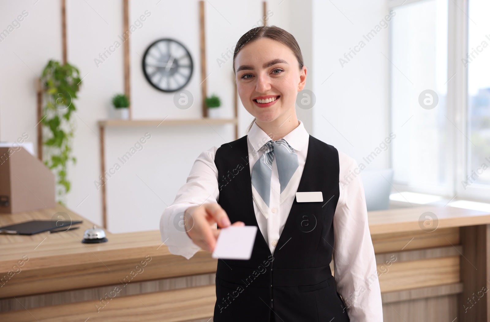 Photo of Portrait of smiling receptionist giving hotel key card indoors