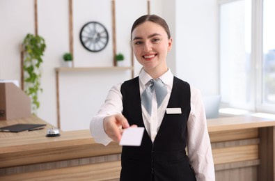 Photo of Portrait of smiling receptionist giving hotel key card indoors