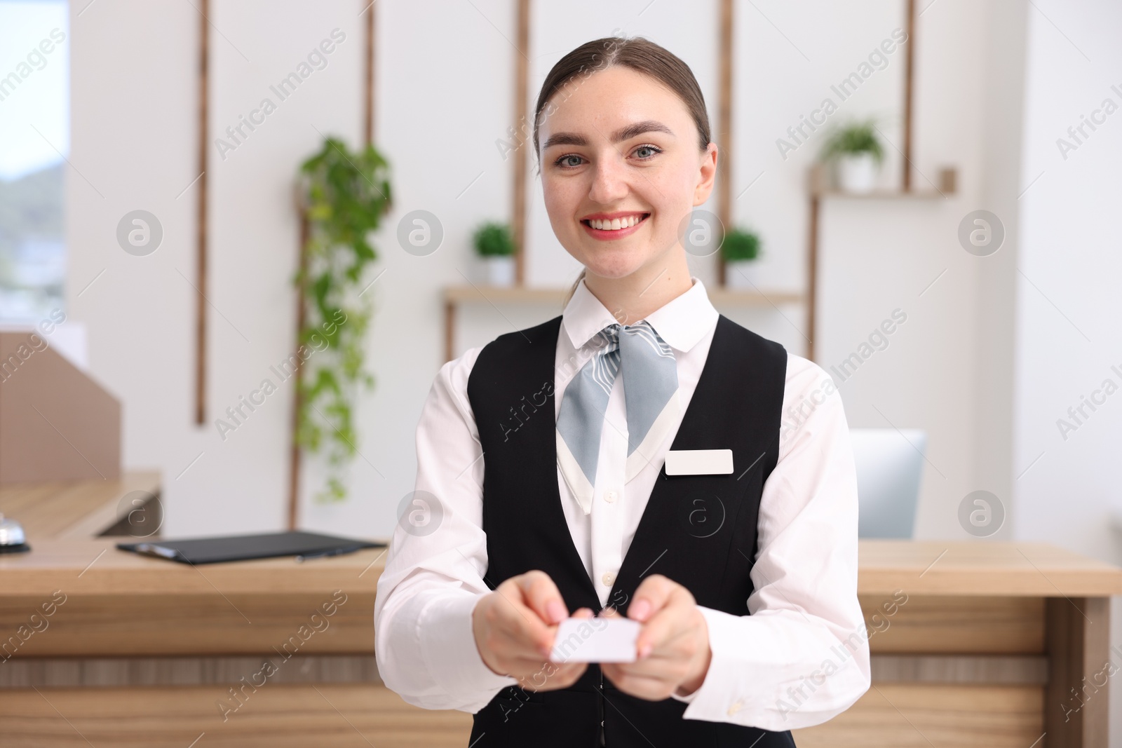 Photo of Portrait of smiling receptionist giving hotel key card indoors