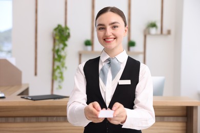 Photo of Portrait of smiling receptionist giving hotel key card indoors
