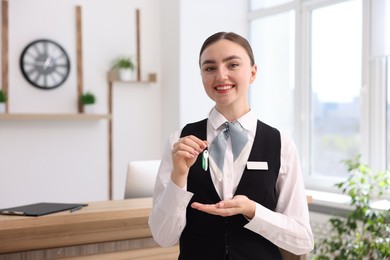 Photo of Portrait of smiling receptionist giving guest room key in hotel